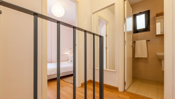 Een gang met een bed, een badkamer en een raam.