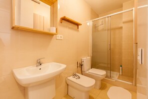 Casa de banho com lavatório, sanita e cabine de duche com vidro.