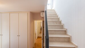 Een trap die leidt naar een plateau met uitzicht op de omgeving, een witte kledingkast en een deur naar een andere kamer.