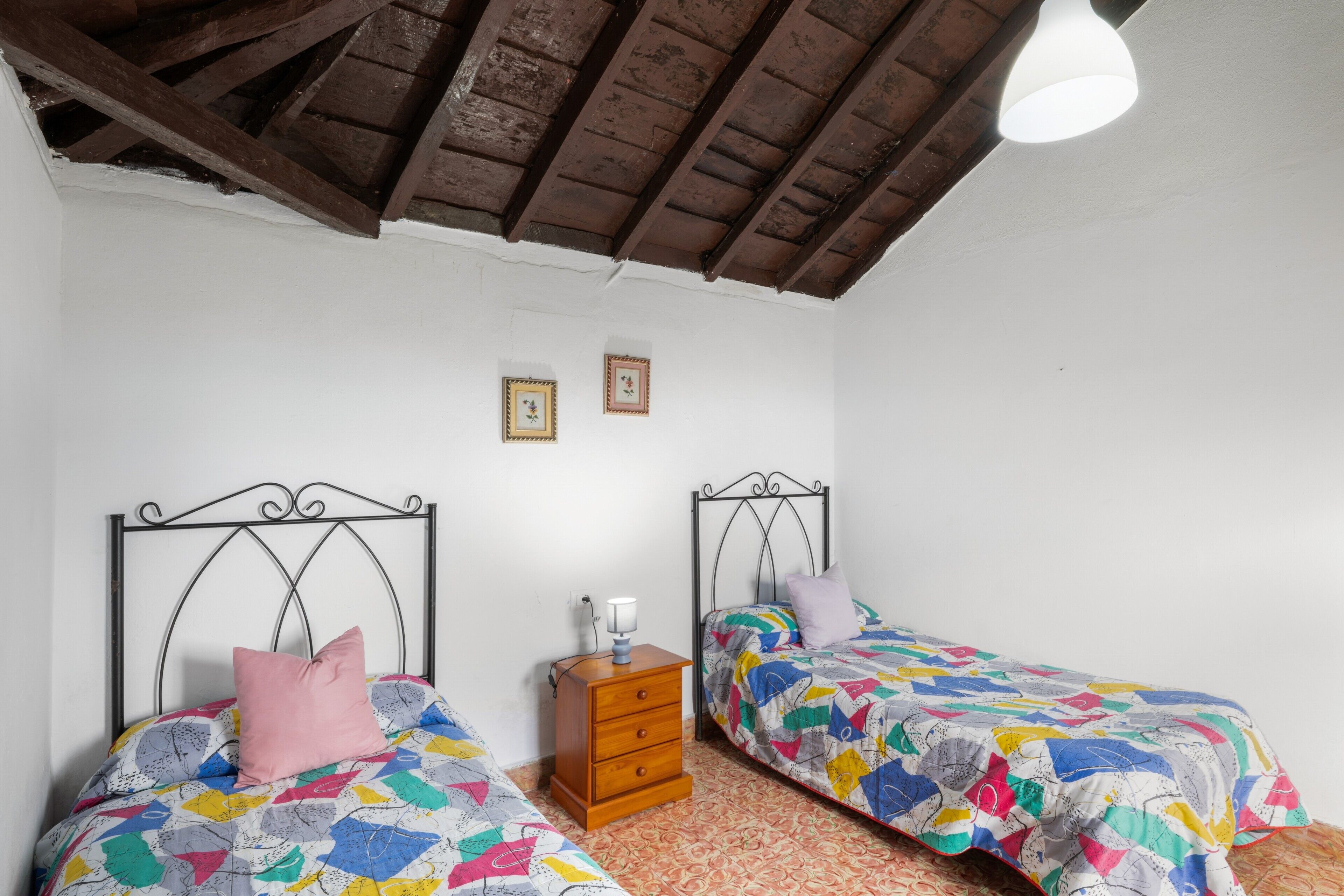 Un dormitorio con dos camas, un aparador de madera y un ventilador de techo.