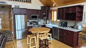 Una cocina con armarios de madera, electrodomésticos de acero inoxidable, una mesa de comedor de madera y un horno empotrado.