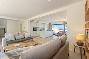 Un salon moderne avec un canapé, une table basse et une vue sur la cuisine et l’espace repas.
