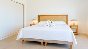 Een hotelkamer met een groot bed, twee nachtkastjes met lampen en een witte deur.