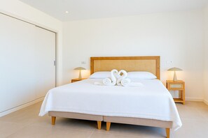 Ein Hotelzimmer mit einem großen Bett, zwei Nachttischen mit Lampen und einer weißen Tür.