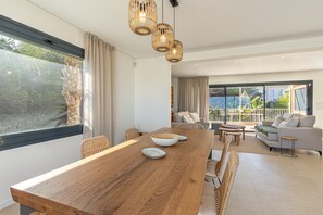 Un espace repas moderne avec une table en bois, des chaises et une vue sur l’extérieur.