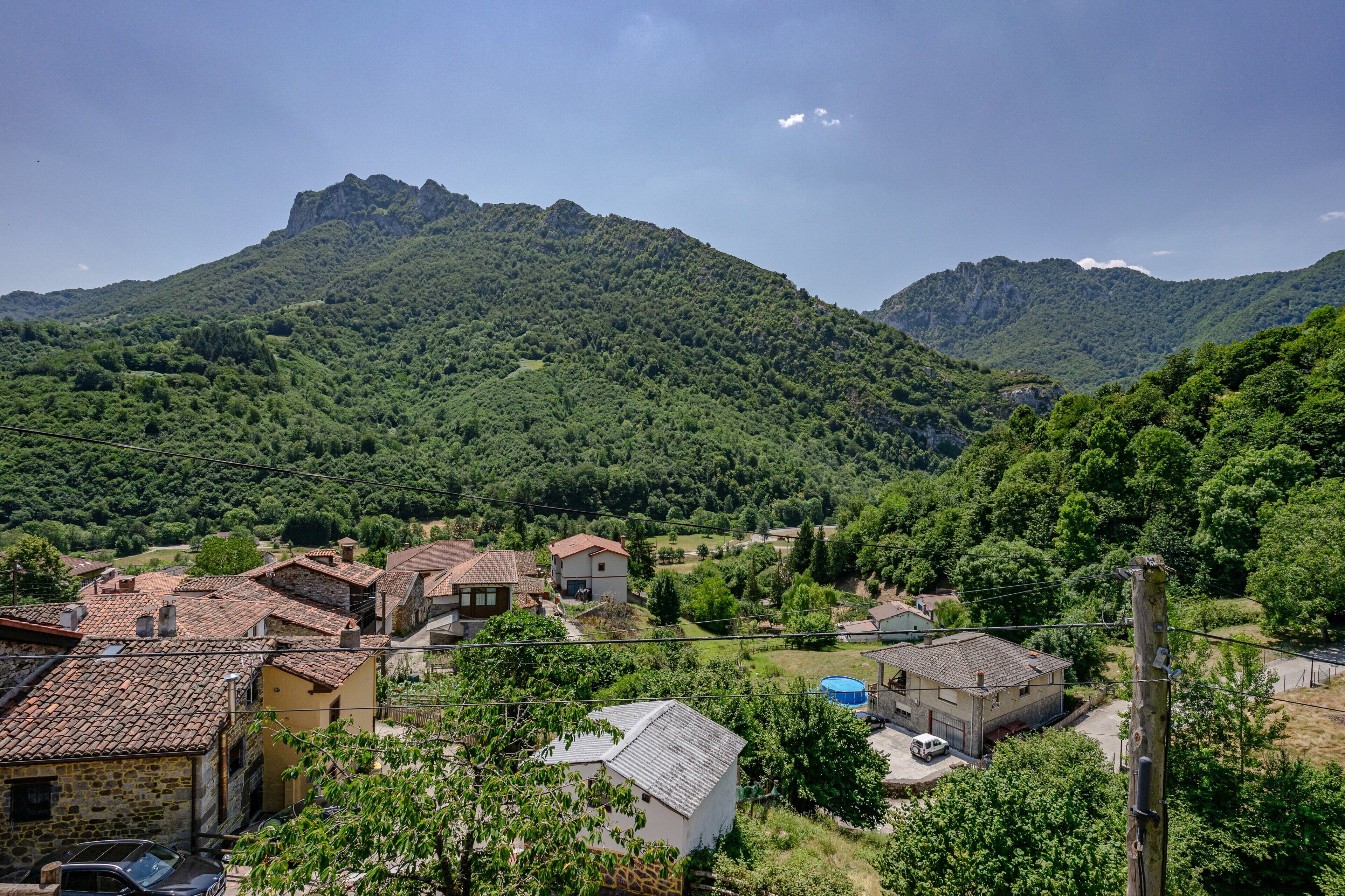Un pueblo rural con edificios de piedra, cielo despejado y montañas al fondo.