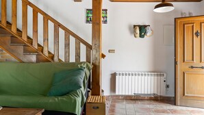 A wooden staircase leading to a green sofa, a radiator, and a door with a handle.