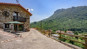 A stone building with a balcony, a wooden fence, and a view of a mountainous landscape.