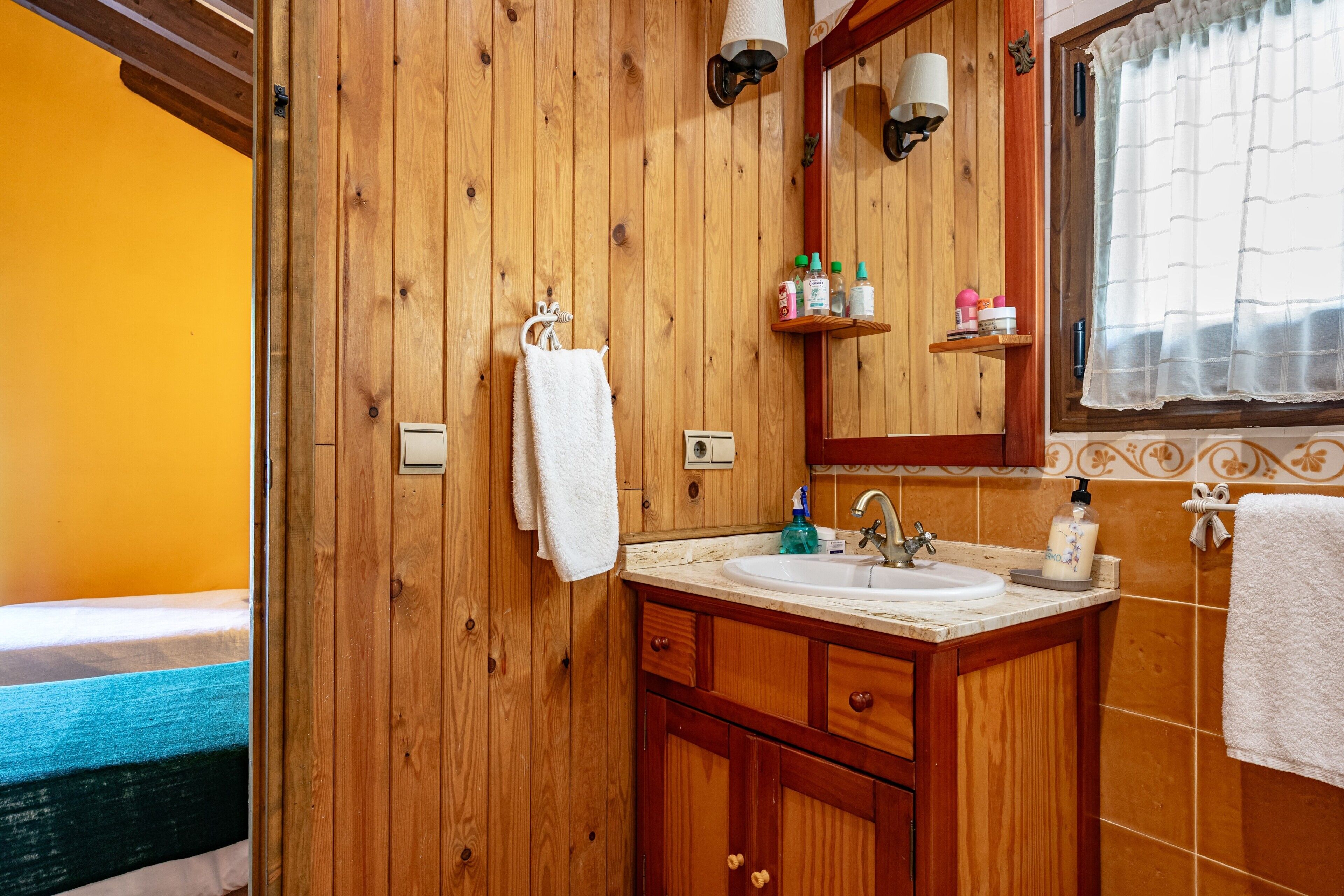 A wooden bathroom with a sink, mirror, and towel rack.