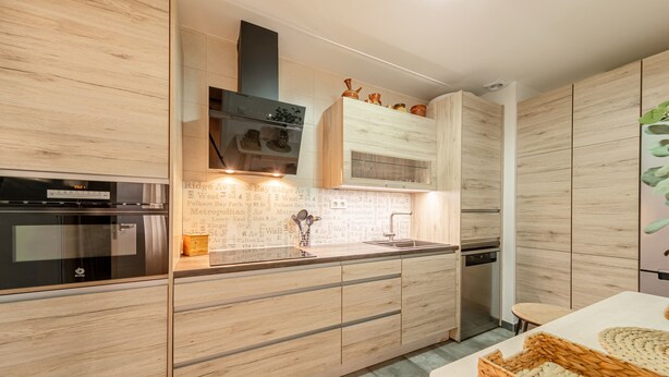 Una cucina moderna con mobili in legno, forno integrato e lavello.