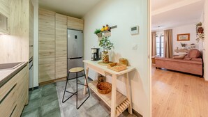 Una cucina compatta con mobili in legno, un tavolo da pranzo e un divano nella zona giorno adiacente.