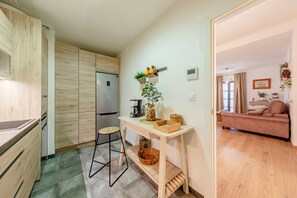 Cozinha compacta com armários de madeira, uma mesa de jantar e um sofá na área de estar adjacente.