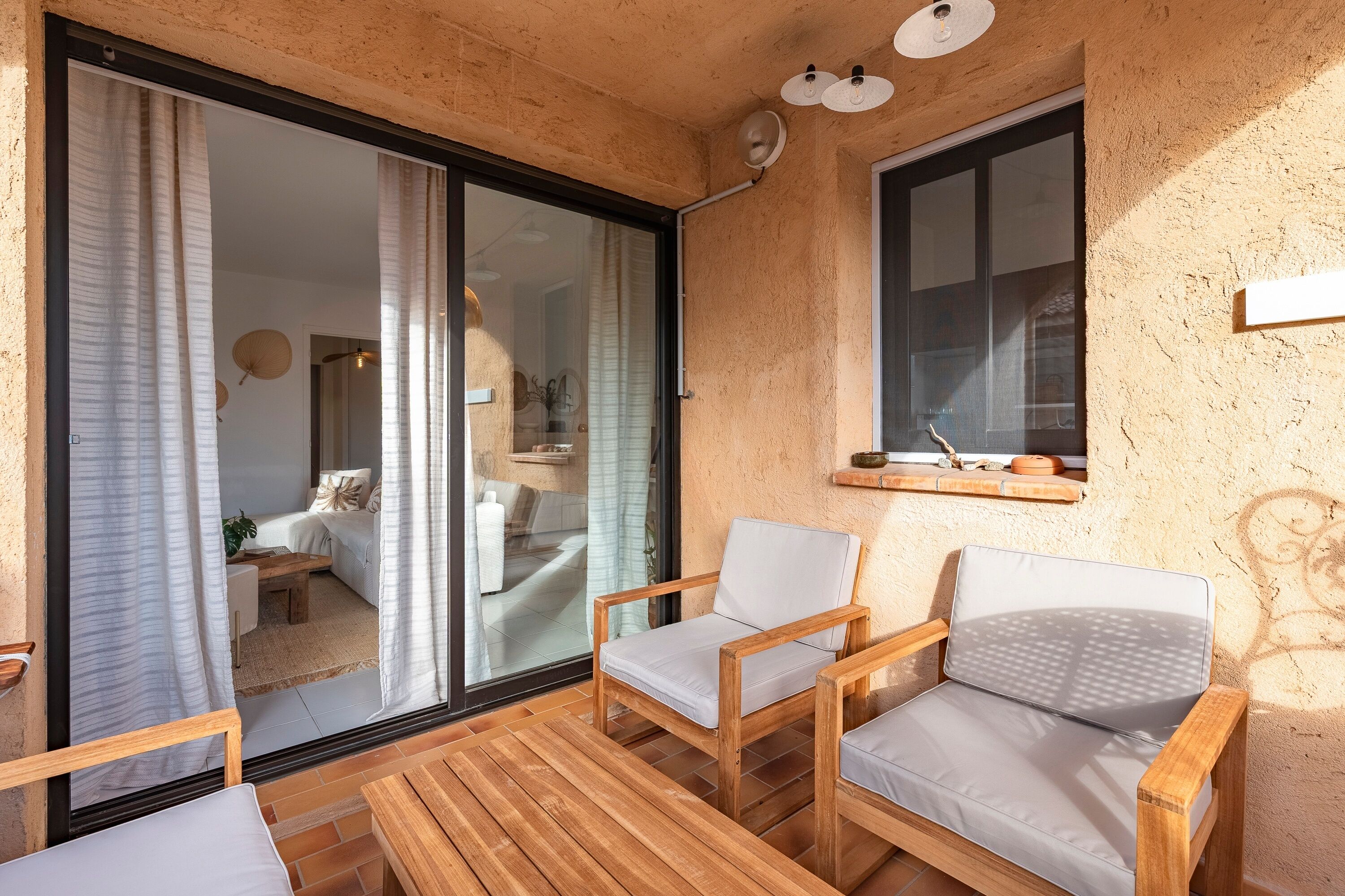 Un espace extérieur accueillant, aménagé avec du mobilier en bois et doté d’une porte en verre donnant accès à une pièce intérieure.