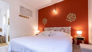 Un lit bien fait, avec une literie blanche, une tête de lit en bois et deux lampes de chevet.