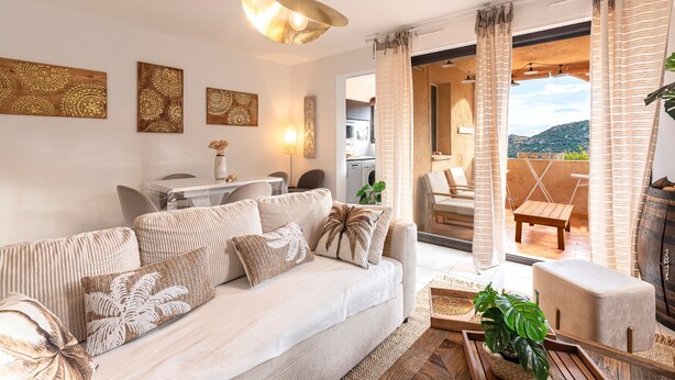 Un salon moderne avec un canapé, des coussins décoratifs et un luminaire suspendu.
