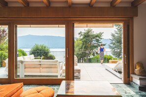 Una sala de estar moderna con un gran ventanal corredera que da a un balcón con vistas a la montaña.