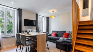 Ein modernes Wohnzimmer mit Essbereich, einer Couch und einer Treppe.