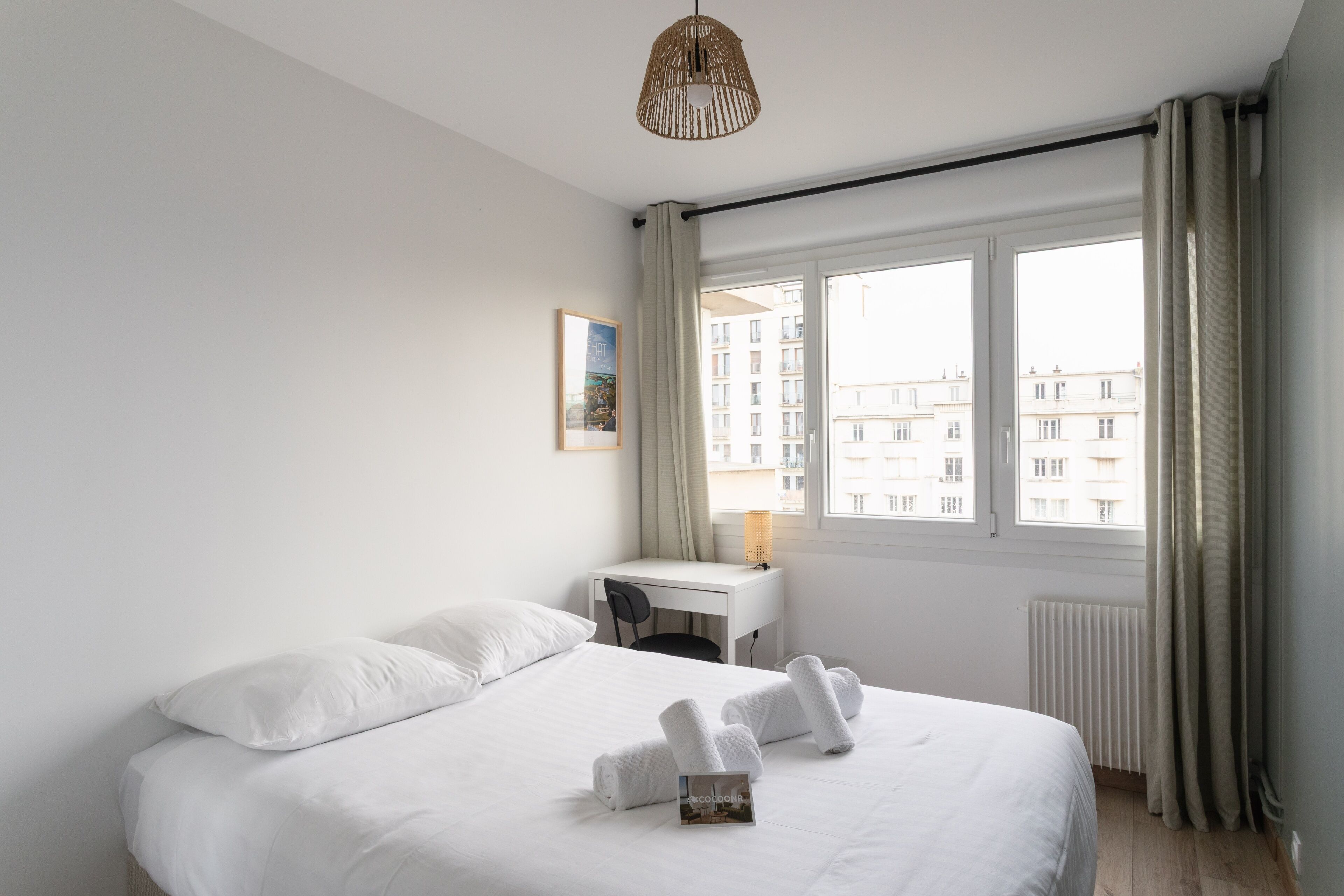 Une chambre d’hôtel avec un lit, un bureau et une fenêtre avec des rideaux.