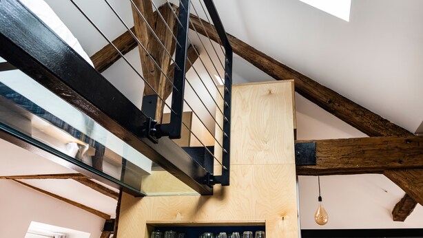 A modern interior with exposed wooden beams, a glass ceiling, and a wooden wall with shelves. - Le Saint Claude - Studio dans le Marais (Paris)