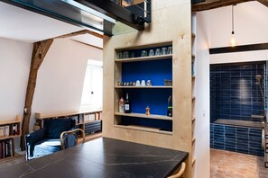 Ein Zimmer mit einem Holztisch, Bücherregalen, einer blauen Akzentwand und einer hängenden Leuchte.