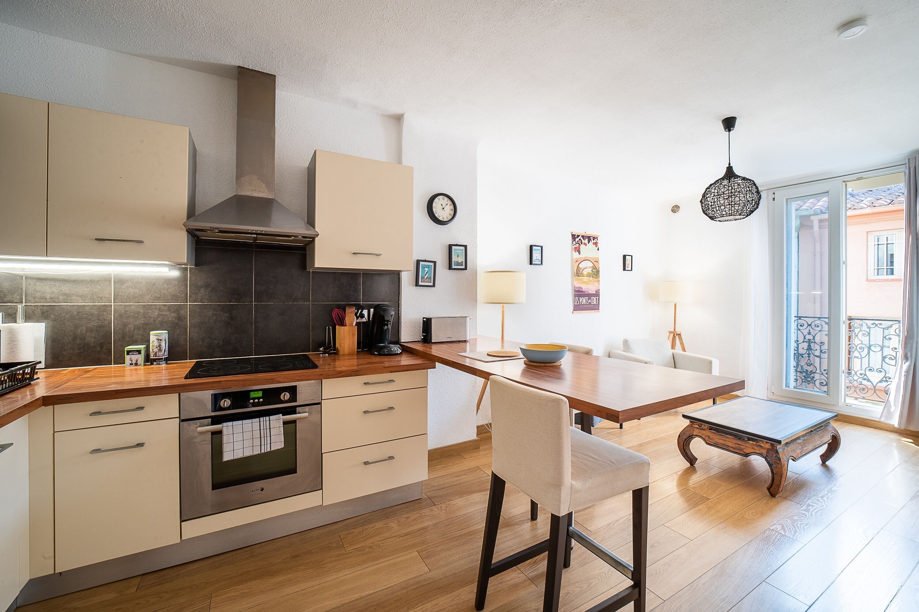 A modern kitchen with wooden countertops, a built-in oven, and a large window offering a view of the outside.