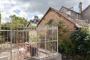 A stone building with a sloped roof, a metal gate, and potted plants.