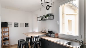 A modern kitchen with a wooden countertop, black stools, a built-in sink, and a window providing natural light.