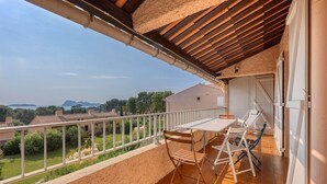 Un balcone con tavolo e sedie, vista sulla zona circostante e pavimento piastrellato.