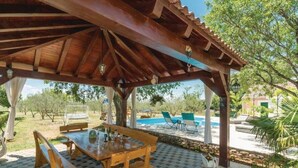 A wooden pergola with a pool table and chairs underneath, surrounded by a checkered patio area. - Holiday Home Marin AS (Drnis)