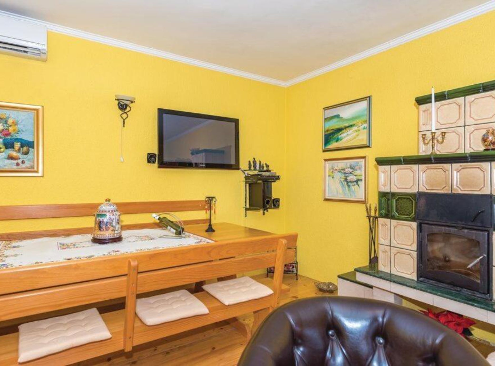 A room with a wooden bench, a television, a fireplace, and artwork on the walls.