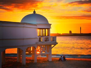 A seaside building with a dome, a balcony, and a view of the ocean at sunset. - Apartment 'La Bella Escondida' with Wi-Fi and Air Conditioning (Cadiz)