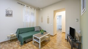 A living room with a green sofa, a white coffee table, a TV on a stand, and a wooden floor. - Apartment 'La Bella Escondida' with Wi-Fi and Air Conditioning (Cadiz)