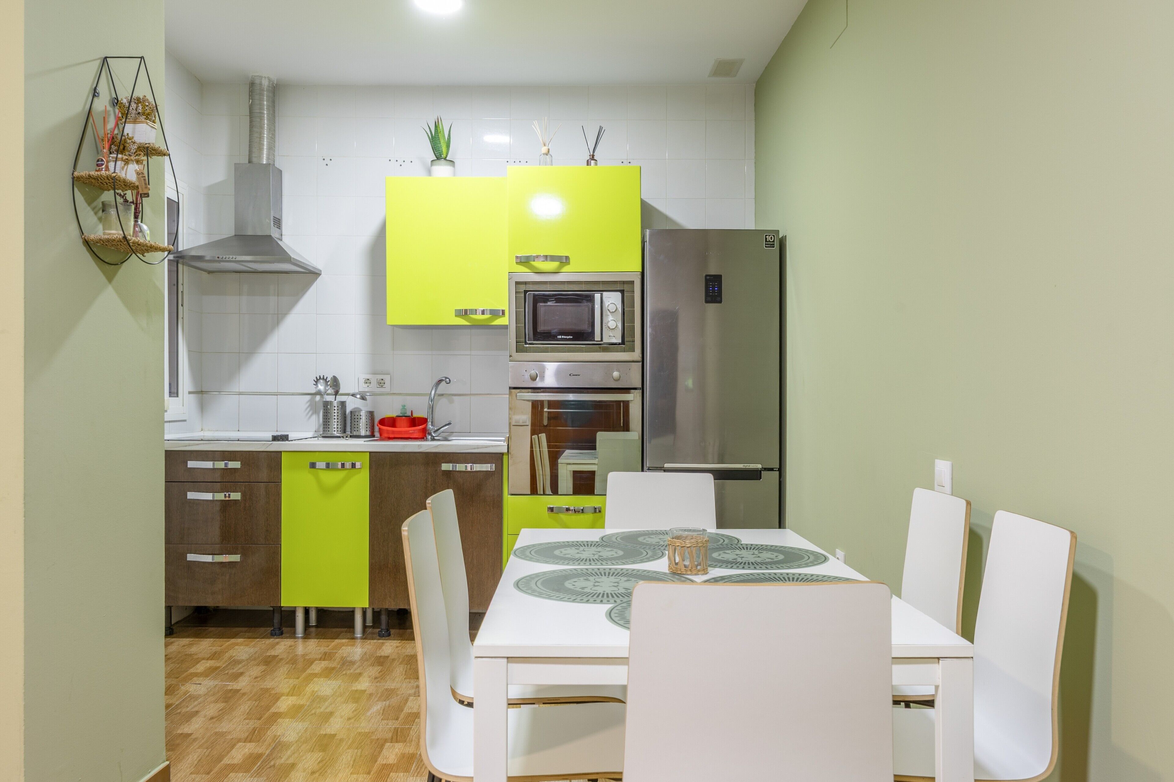 Una cocina moderna con una mesa de comedor, sillas, microondas, horno y refrigerador.