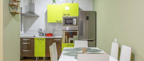 Una cocina moderna con una mesa de comedor, sillas, microondas, horno y refrigerador.
