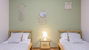 A room with two beds, a bedside table with a lamp, a wall hanging, and a framed picture. - Apartment 'La Bella Escondida' with Wi-Fi and Air Conditioning (Cadiz)