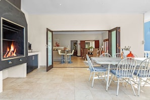 A modern kitchen with a built-in fireplace, a dining area with a table and chairs, and a view into the dining room. - Villa 17 on Graham (Cape Town)