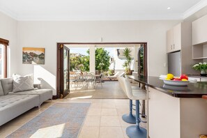 A modern kitchen with a dining area, a sofa, and a view of the outdoors. - Villa 17 on Graham (Cape Town)