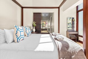 Ein modernes Hotelzimmer mit einem großen Bett, einem Nachttisch, einem Spiegel und Blick auf den Flur.