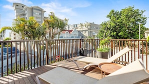 A balcony with wooden flooring, two lounge chairs, and potted plants. - Villa 17 on Graham (Cape Town)