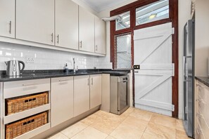 A modern kitchen with white cabinets, a stainless steel refrigerator, and a dishwasher. - Villa 17 on Graham (Cape Town)