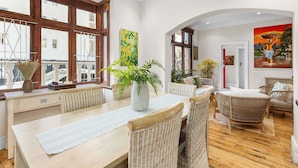 A spacious room with a wooden dining table, wicker chairs, and large windows. - Villa 17 on Graham (Cape Town)