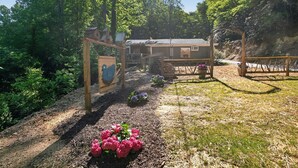 Un espace extérieur rustique agrémenté de structures en bois, un jardin fleuri et un bâtiment visible au loin.