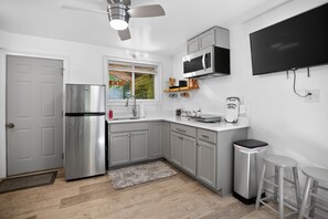 A modern kitchen with grey cabinets, a stainless steel refrigerator, a microwave, and a TV mounted on the wall. - Lamb Mountain Retreat - Pets Welcome! (Hendersonville)