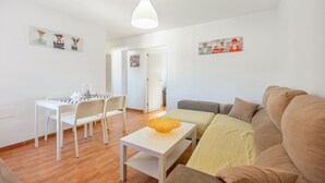 En stue med sofa, spisebord med stole, et lille bord med en skål og billedkunst på væggene.