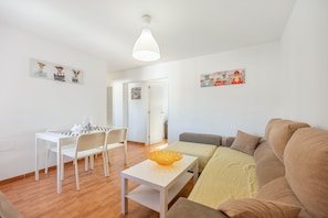 A living room with a sofa, a dining table with chairs, a small table with a bowl, and artwork on the walls. - Apartment 'The Bright Beauty' with Wi-Fi and Air Conditioning (Cadiz)