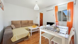 En moderne stue med sofa, spisebord og fjernsyn.