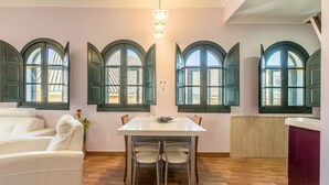 Un espace repas comprenant une table et des chaises, un canapé blanc et des fenêtres en arc de cercle.