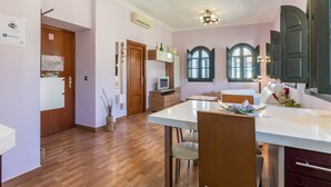 Une cuisine moderne avec un plancher en bois, un coin repas doté d’une table blanche et un téléviseur encastré.