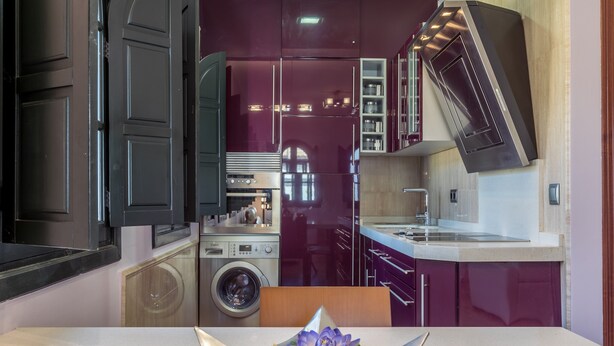 Une cuisine moderne équipée d’un lave-linge intégré, un coin repas avec une table et un arrangement floral décoratif.