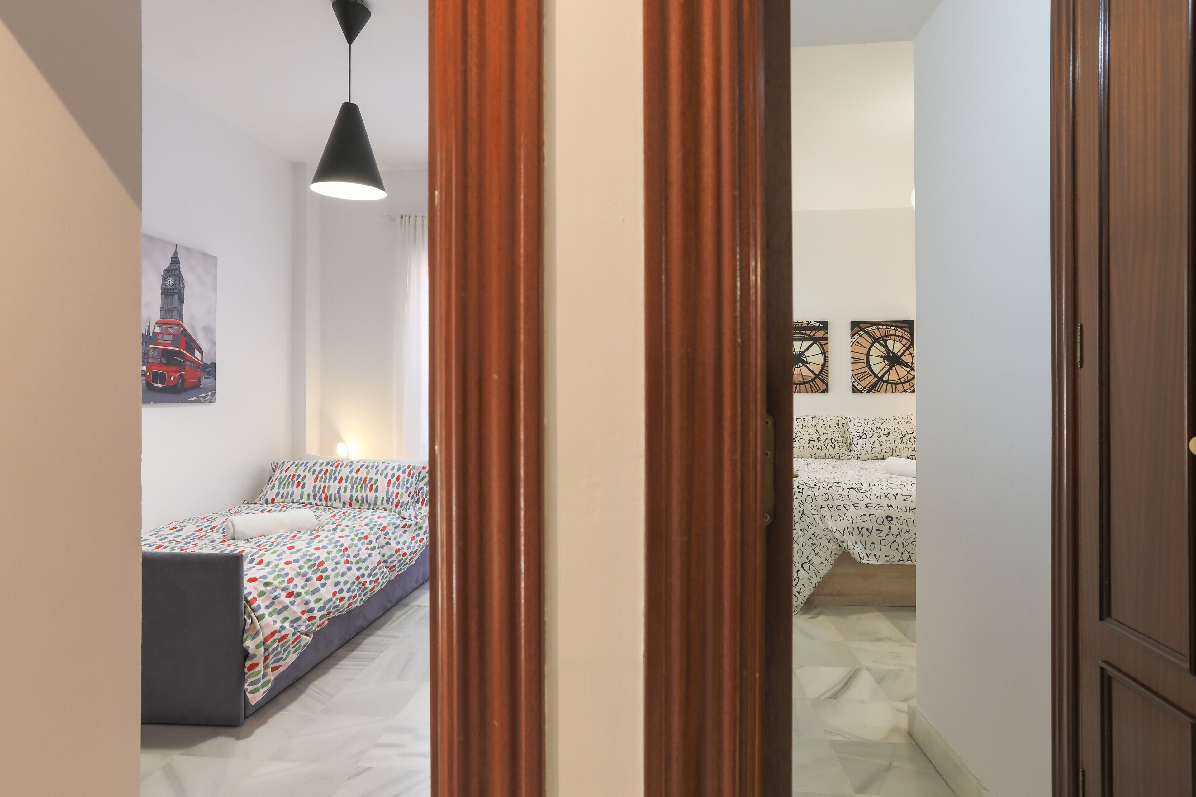 A bedroom with a bed, a desk, and a chair. There is a door leading to another room.